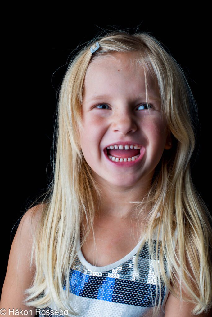Portrett av jente som ler, innendørs, blits